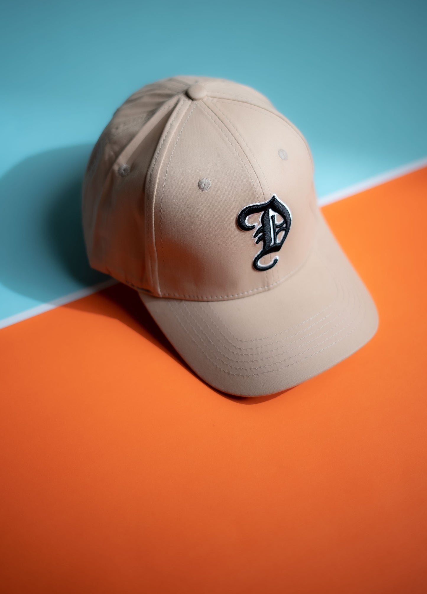 Beige cap with a logo on an orange and blue background in Pakistan by Caps Nation