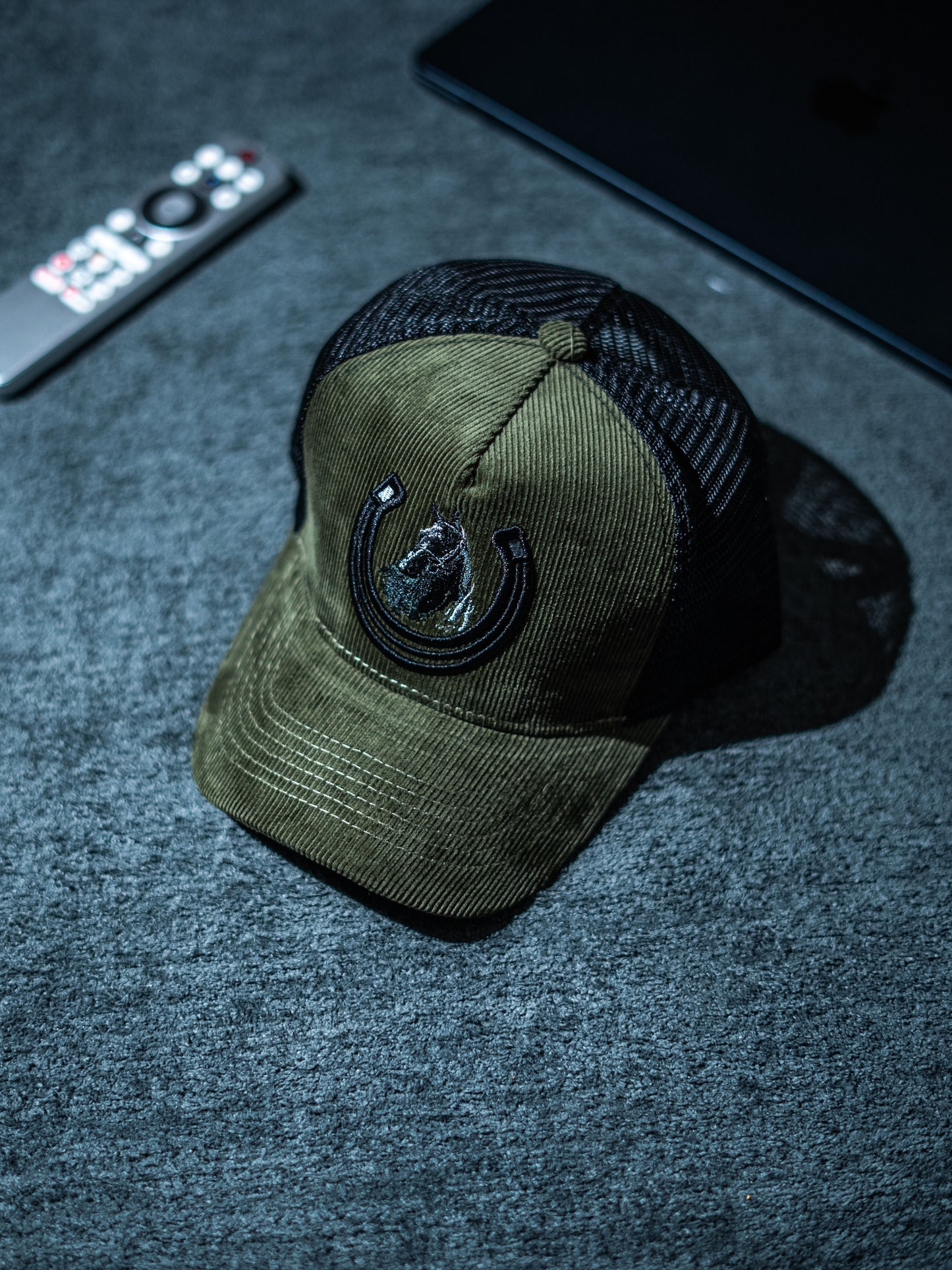 Green cap with black mesh back on a dark textured surface in Pakistan by Caps Nation