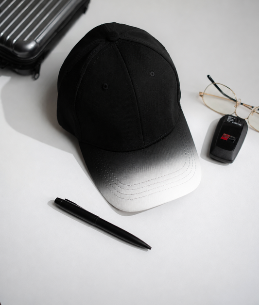 Black cap, pen, glasses, and suitcase on a white surface