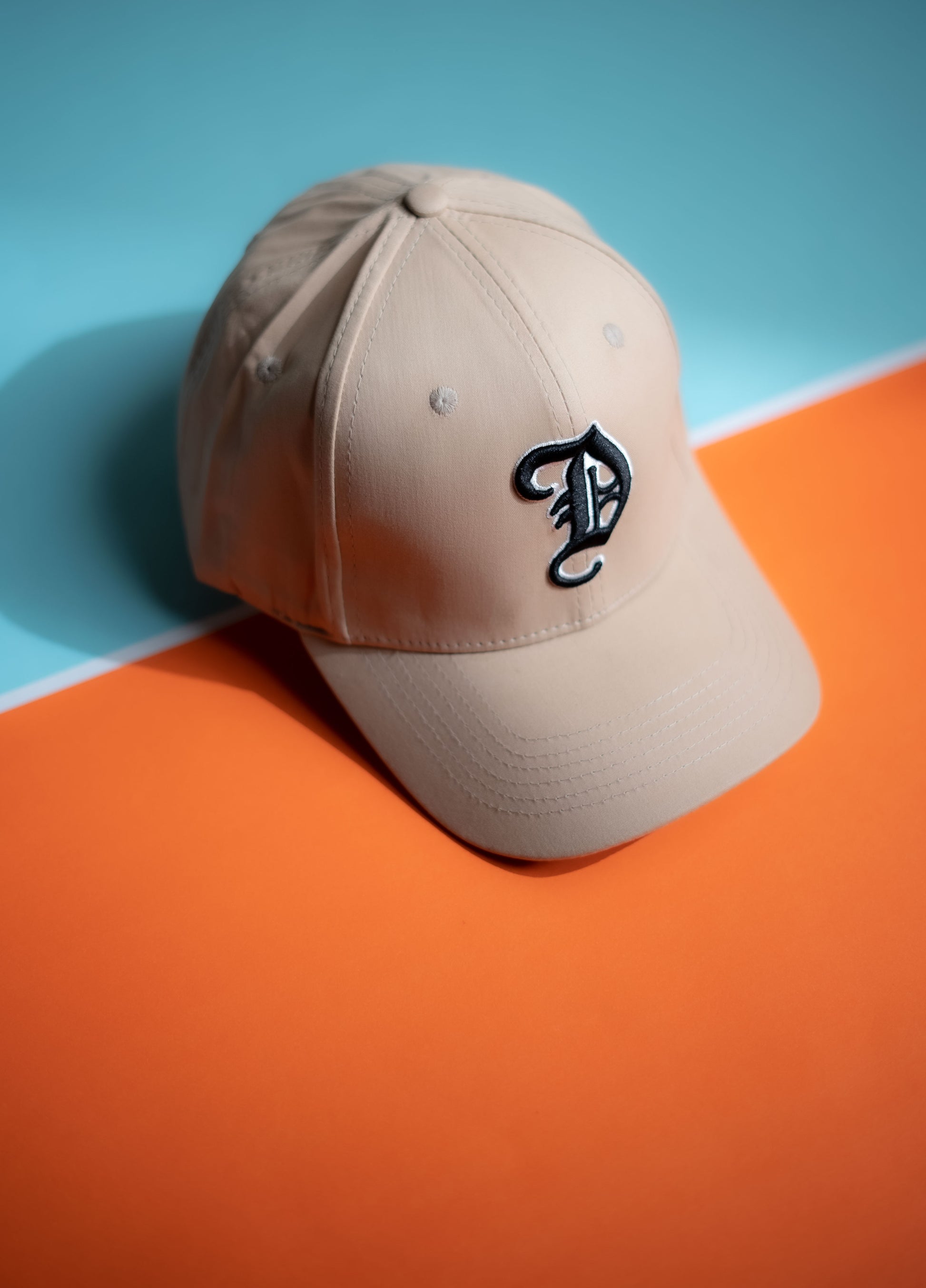 Beige cap with a logo on an orange and blue background in Pakistan by Caps Nation