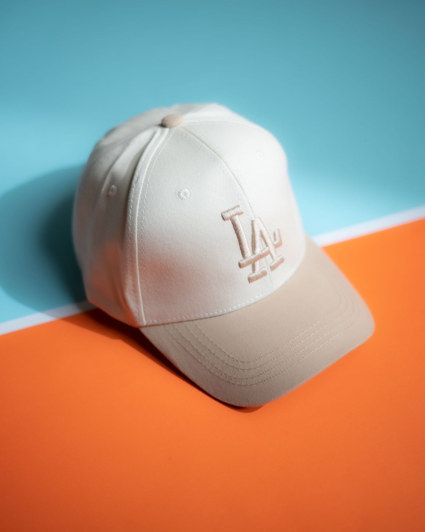 Beige baseball cap with logo on a blue and orange background in Pakistan by Caps Nation