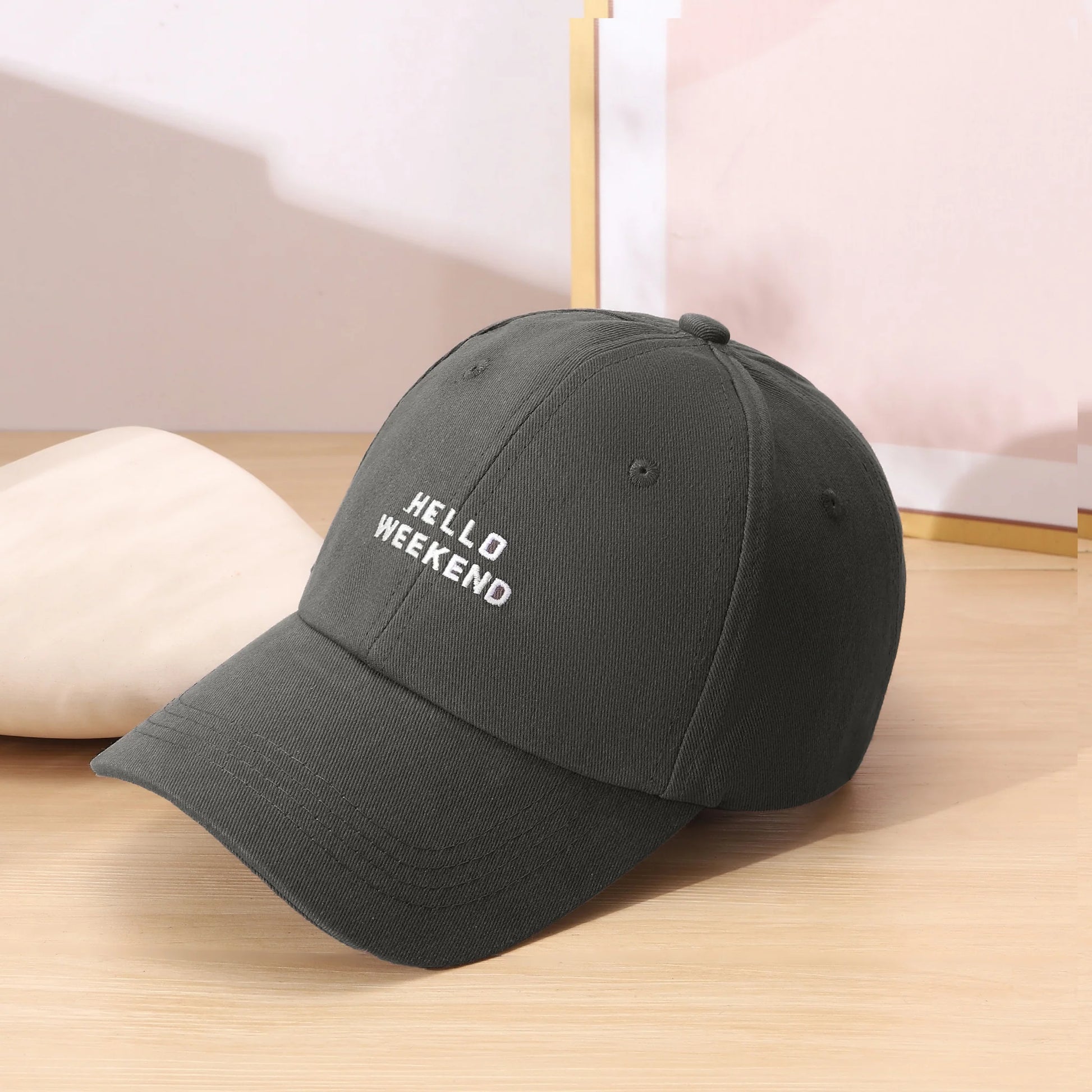Black cap with 'HELLO WEEKEND' text on a wooden surface in Pakistan by Caps Nation