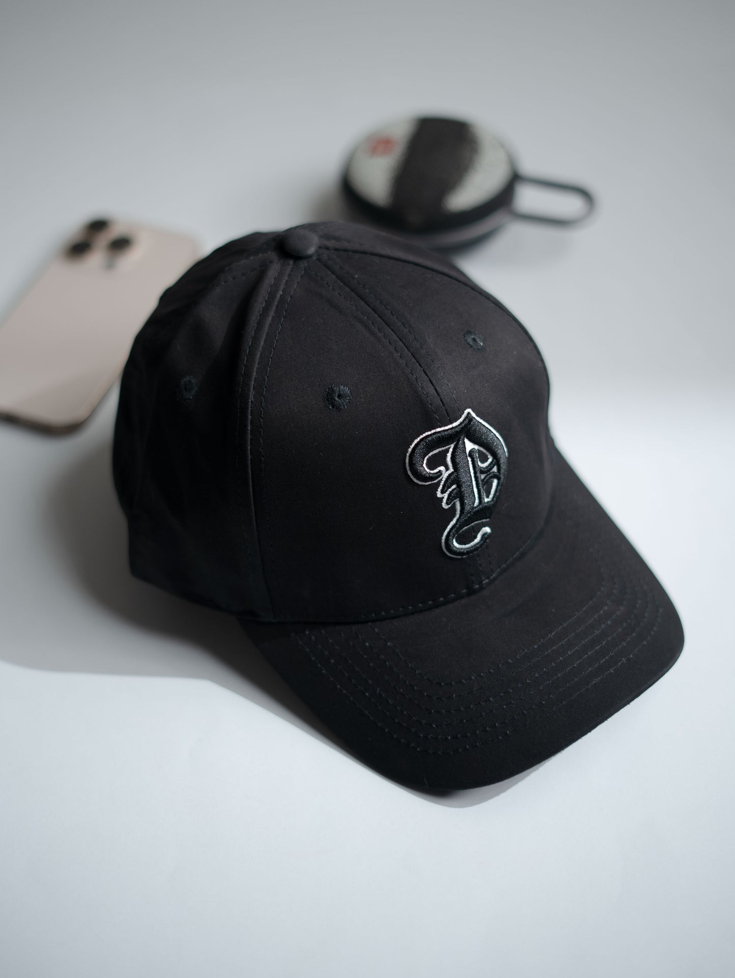 Black cap with a logo on a light gray background in Pakistan by Caps Nation