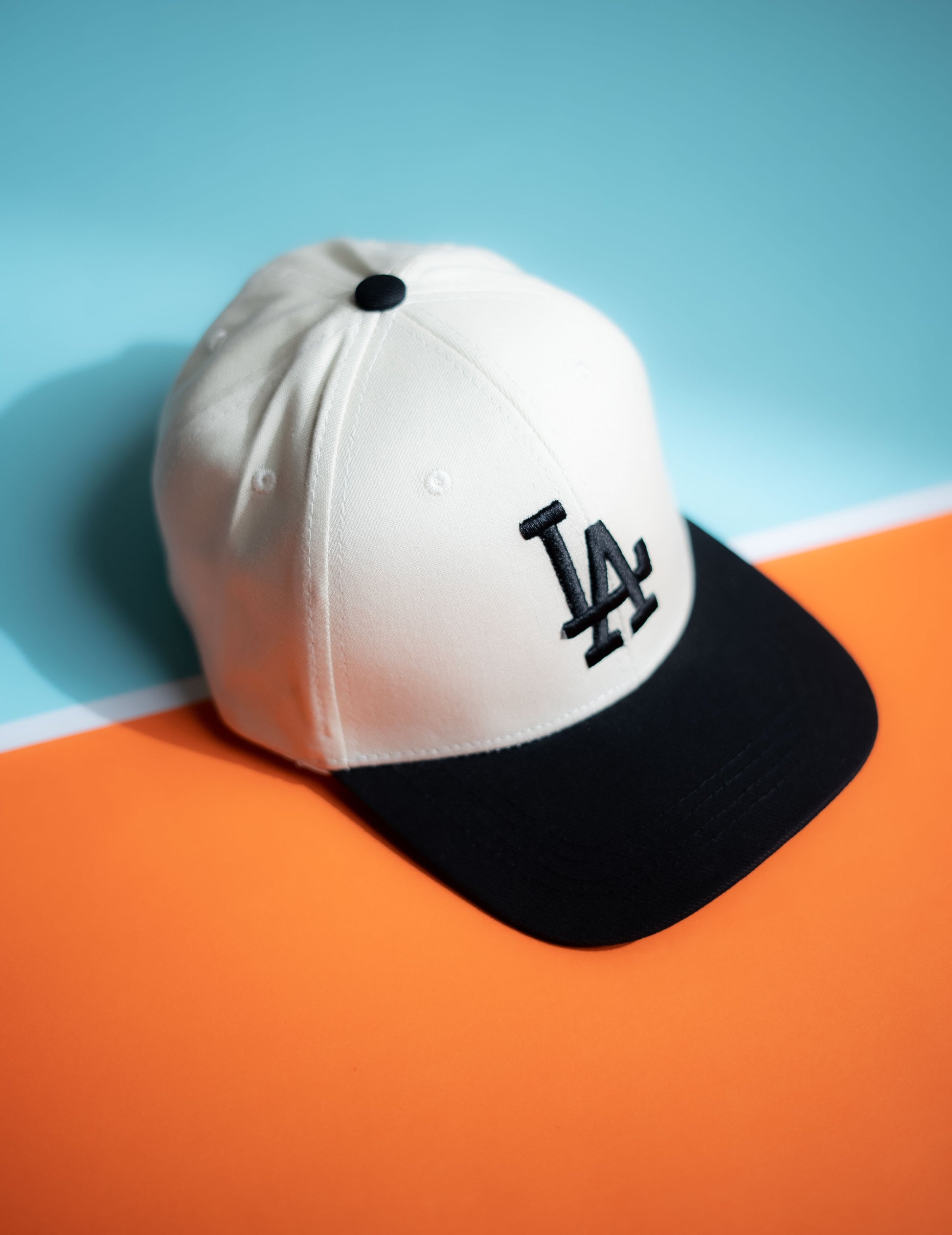 White and black cap with a logo on an orange and blue background in Pakistan by Caps Nation