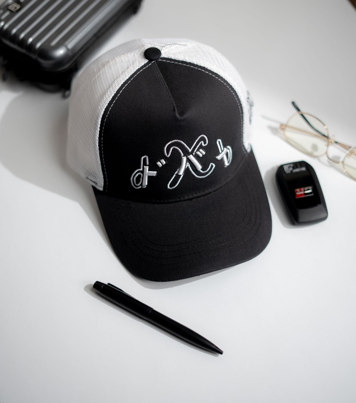 Black and white cap with a logo on a white surface with a pen and phone in Pakistan by Caps Nation