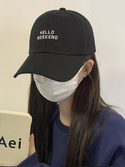 Person wearing a black cap with 'HELLO WEEKEND' text, holding a tablet in Pakistan by Caps Nation