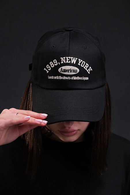 Black cap with '1989, New York' text worn by a person against a dark background in Pakistan by Caps Nation