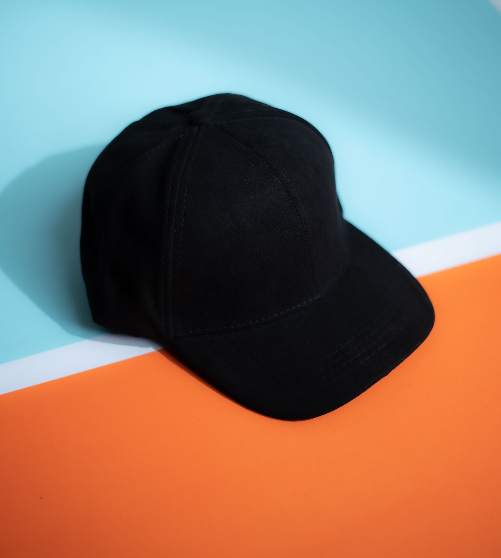 Black cap on a colorful background with blue and orange sections in Pakistan by Caps Nation