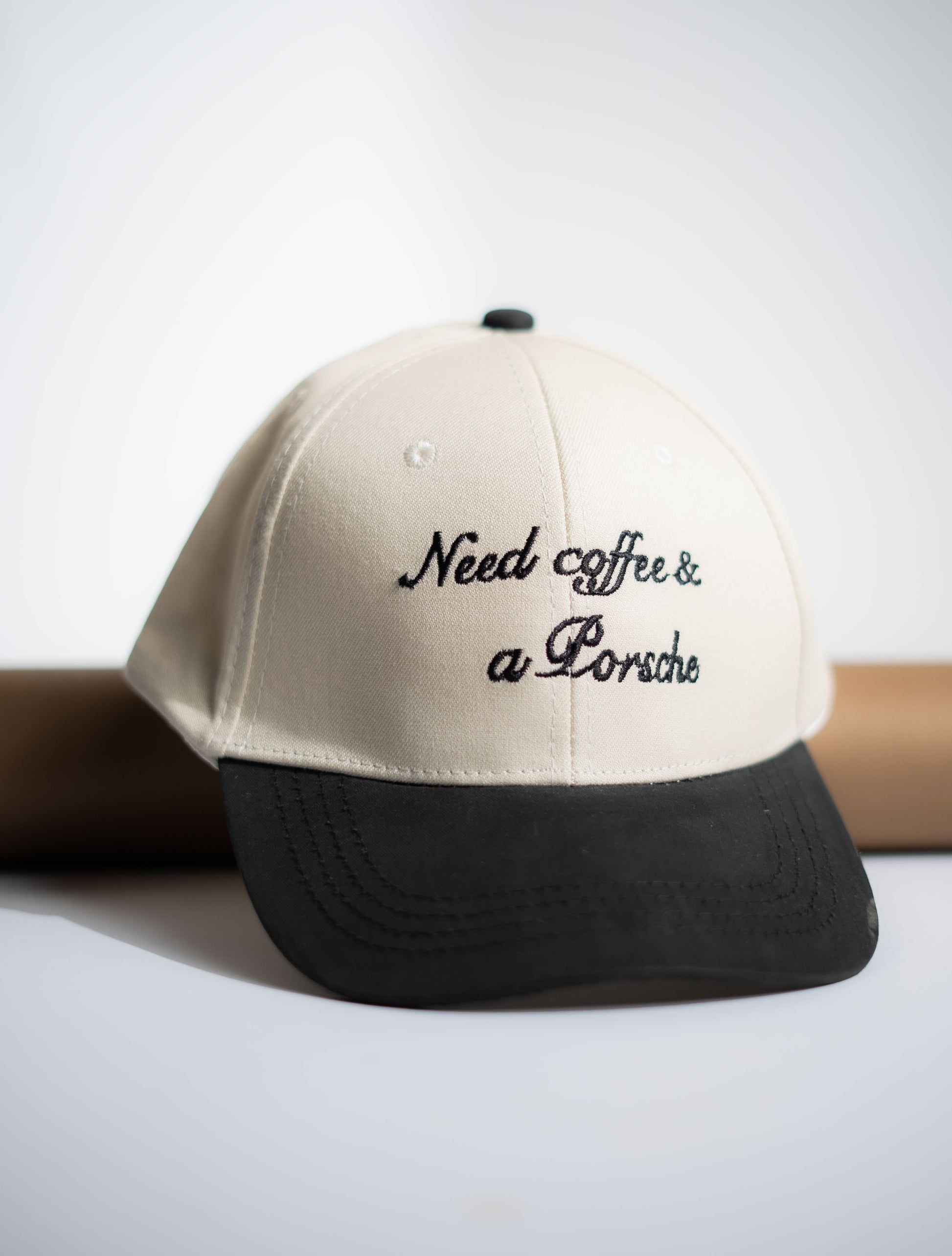 Beige and black cap with 'Need coffee & a Porsche' text on a white background in Pakistan by Caps Nation