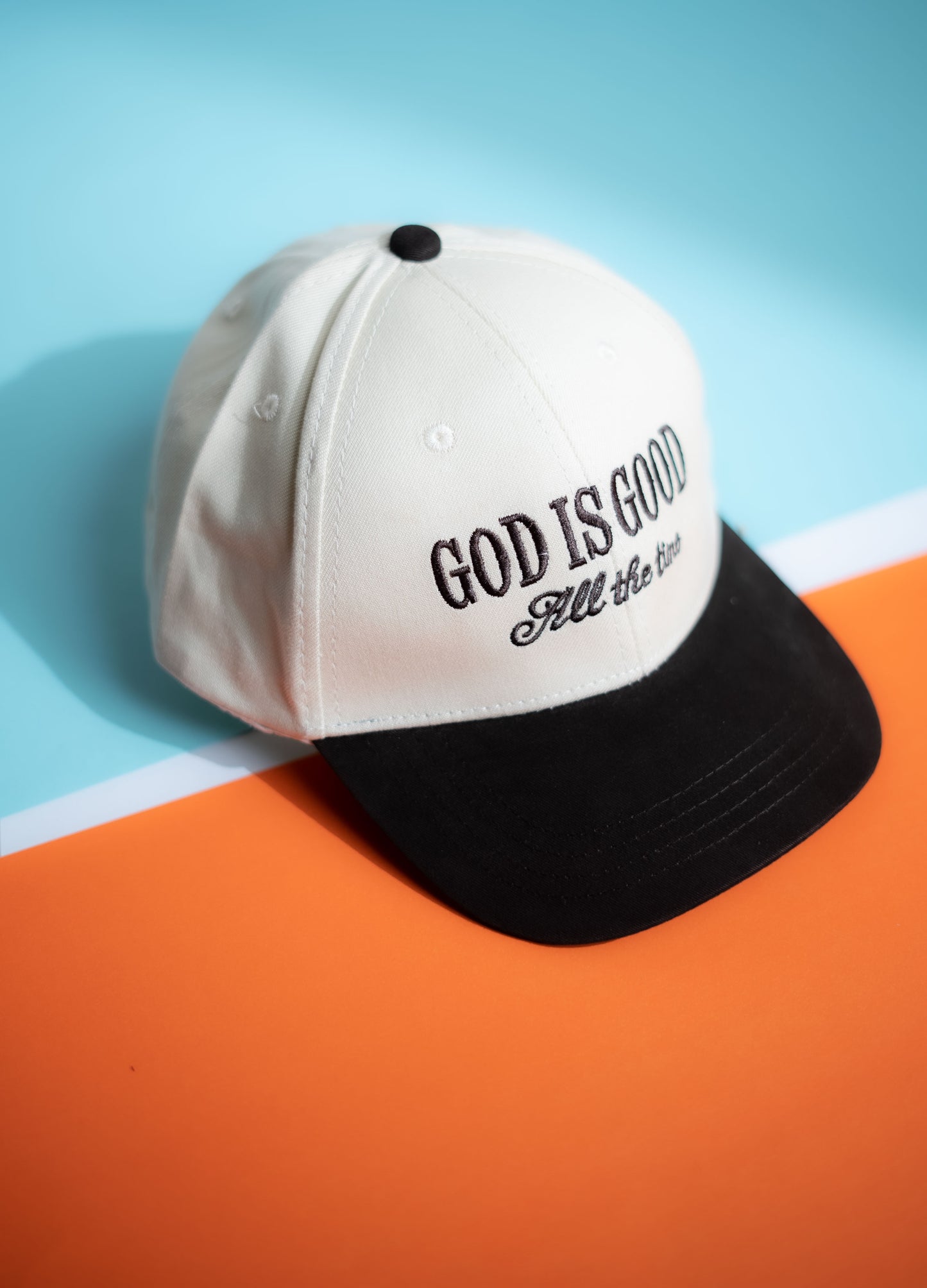 White cap with 'GOD IS GOOD All the Time' text on a blue and orange background in Pakistan by Caps Nation