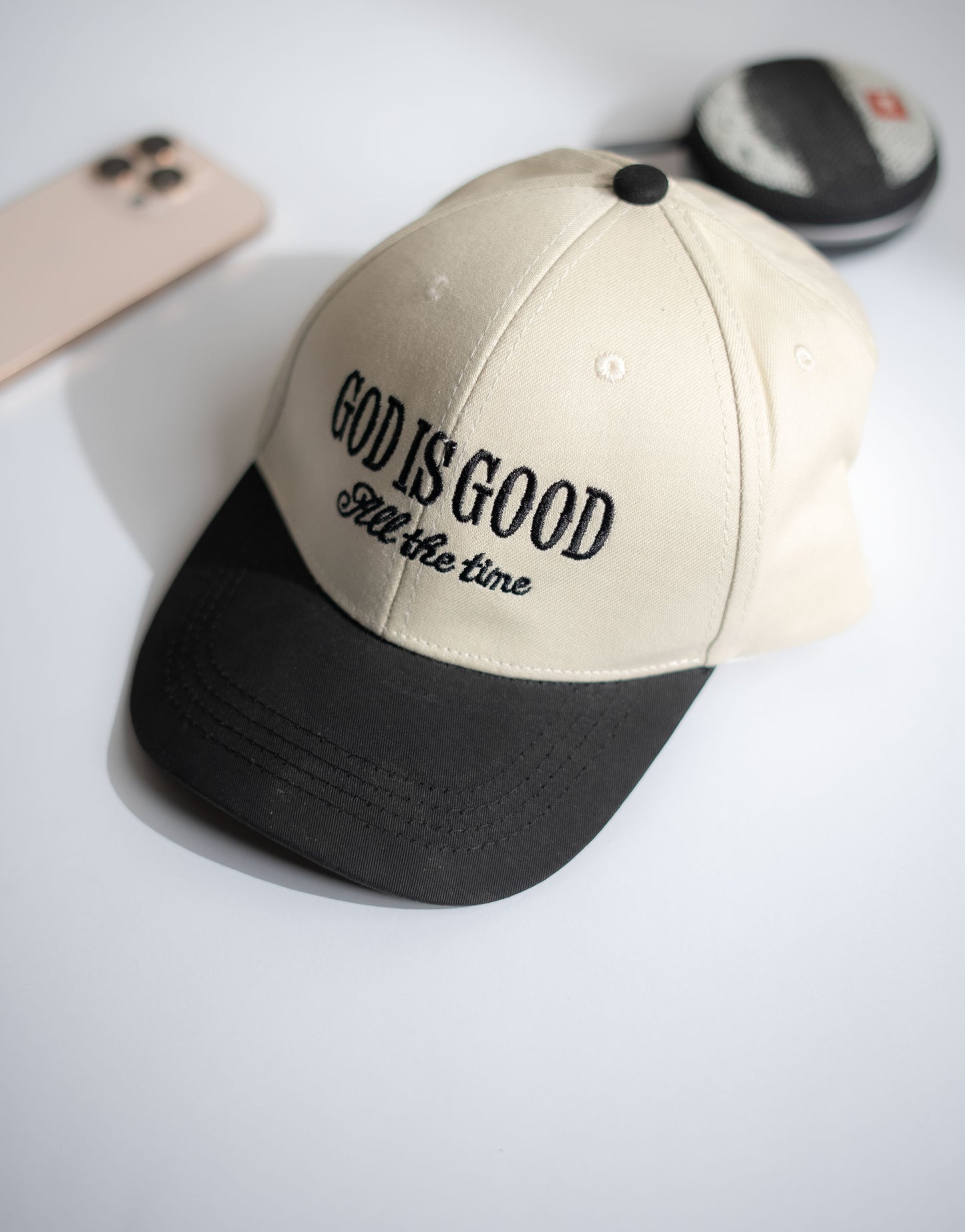 Beige and black cap with 'God is good all the time' text on a white surface in Pakistan by Caps Nation