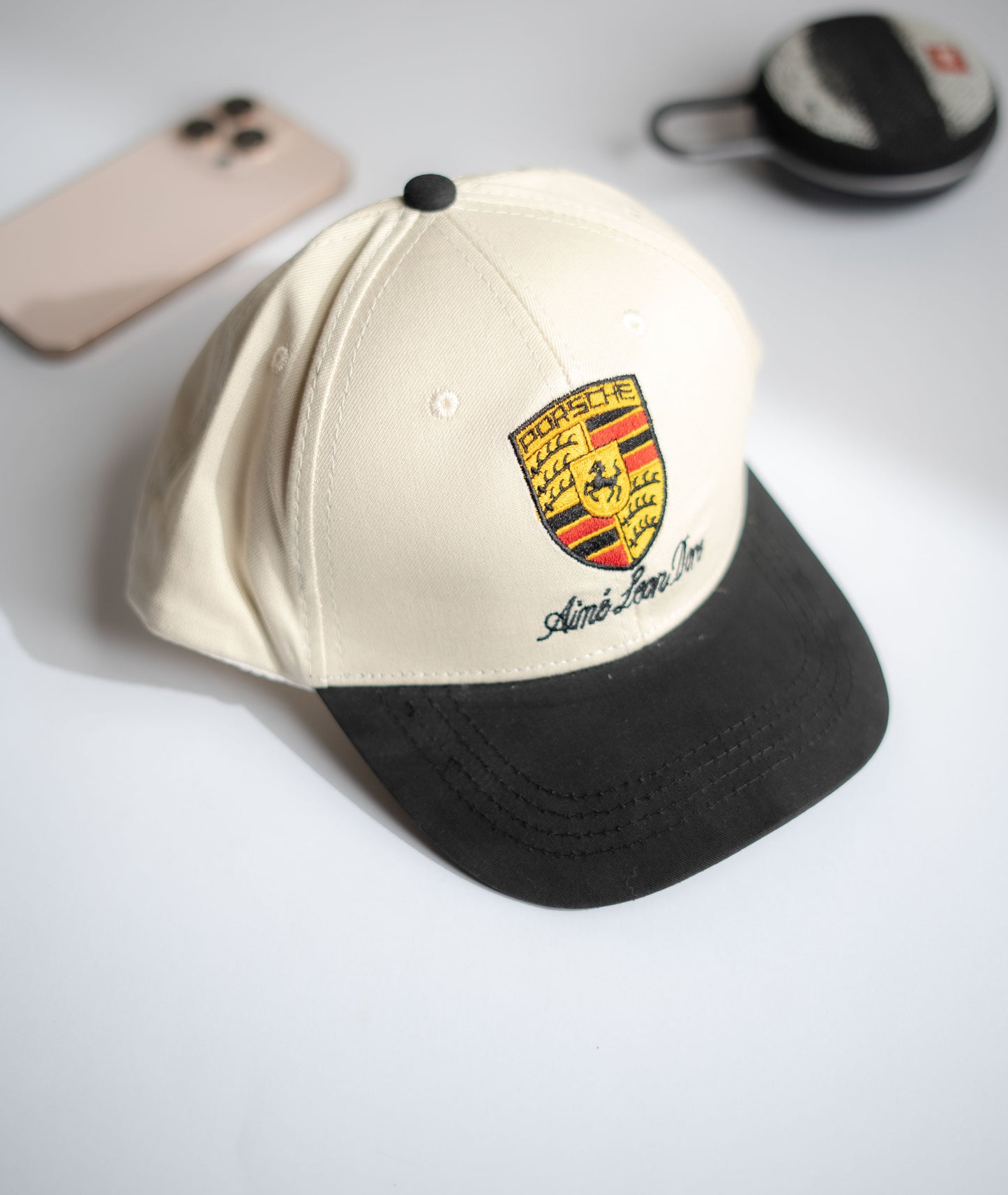 Beige and black cap with a logo on a light gray surface in Pakistan by Caps Nation