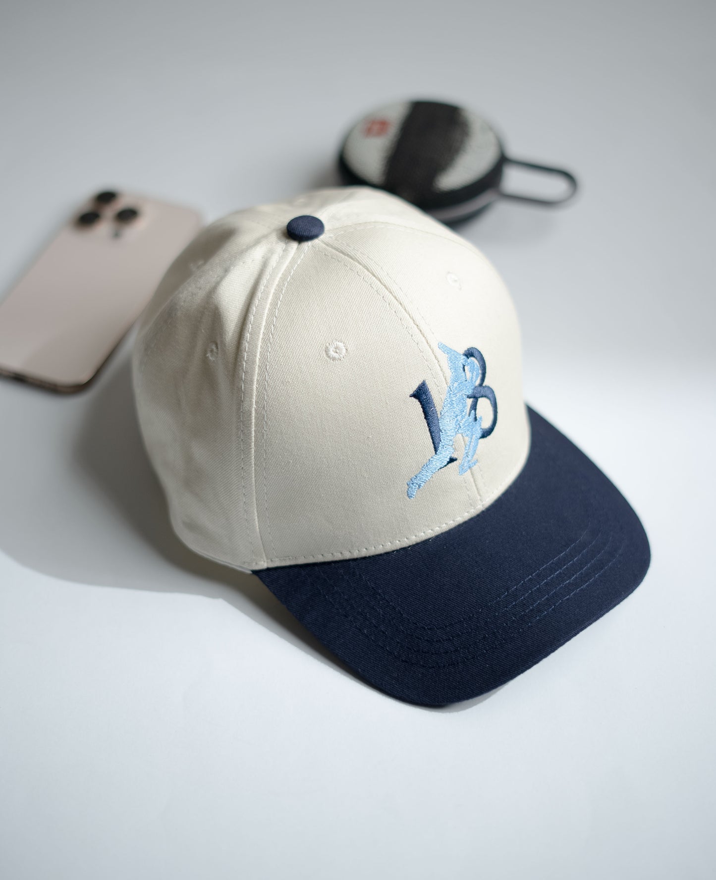 Beige and navy cap with a logo on a light gray surface in Pakistan by Caps Nation