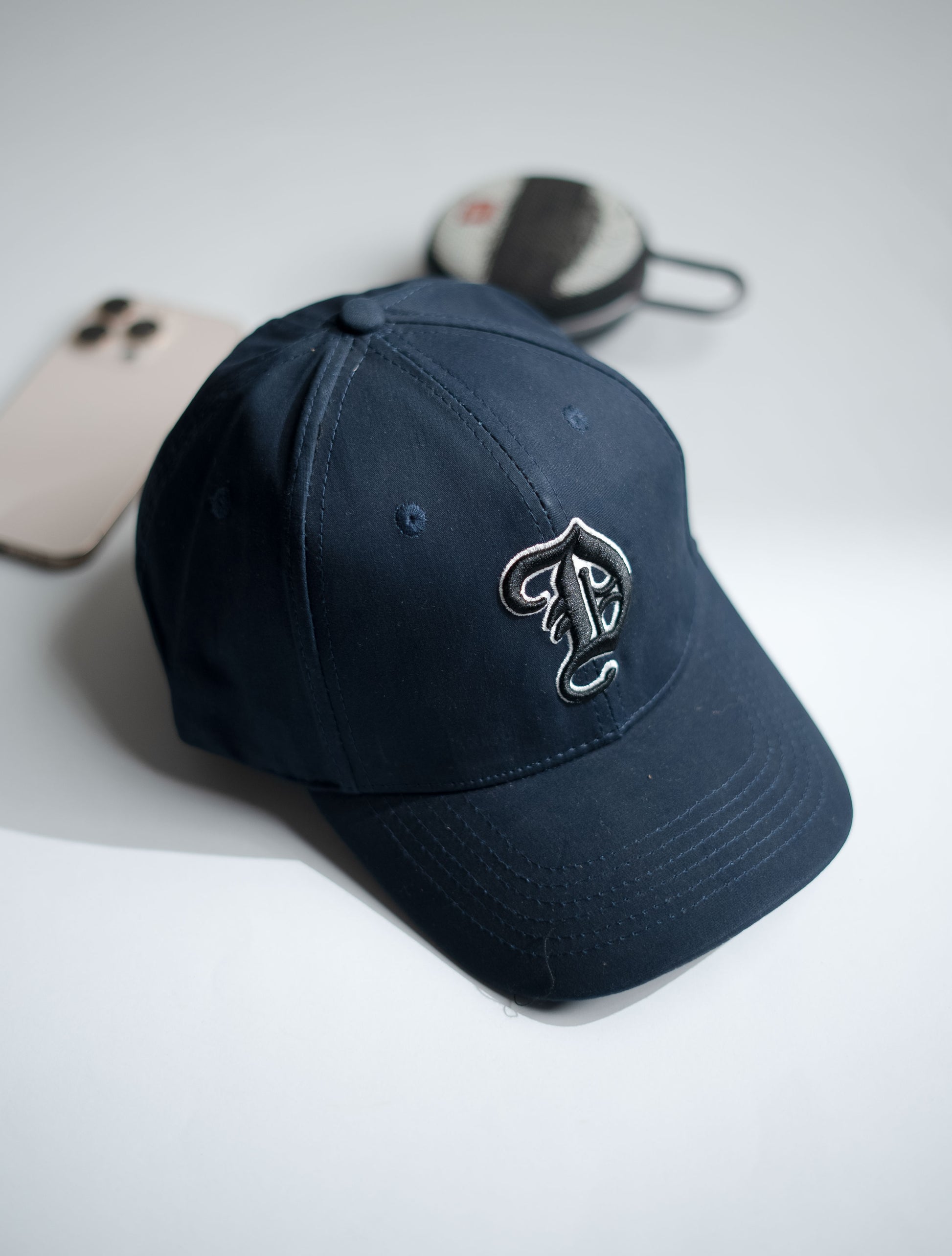 Navy blue cap with a logo on a light gray surface in Pakistan by Caps Nation