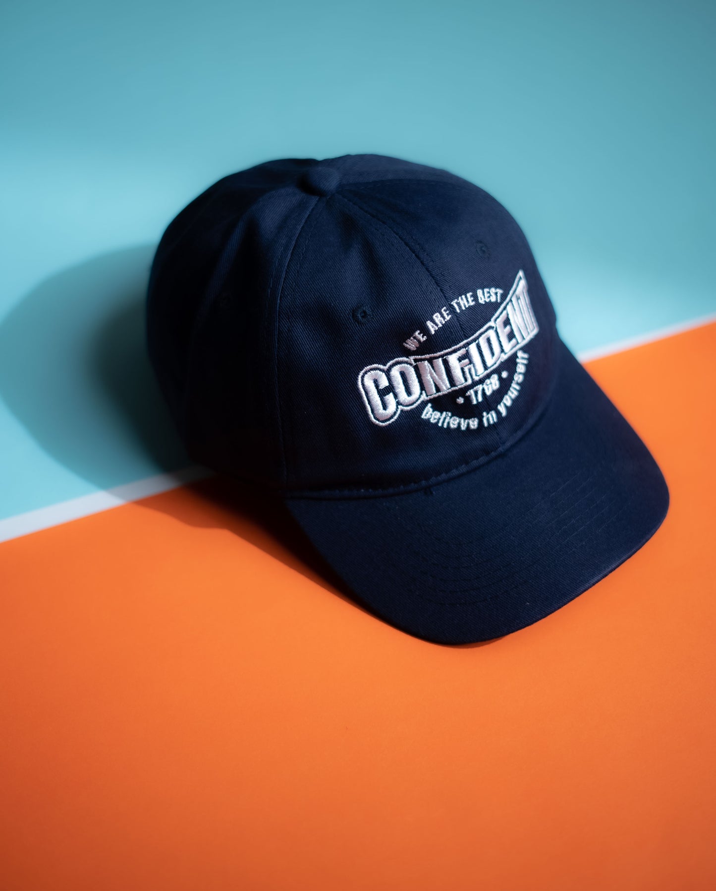 Black cap with white text on a blue and orange background in Pakistan by Caps Nation