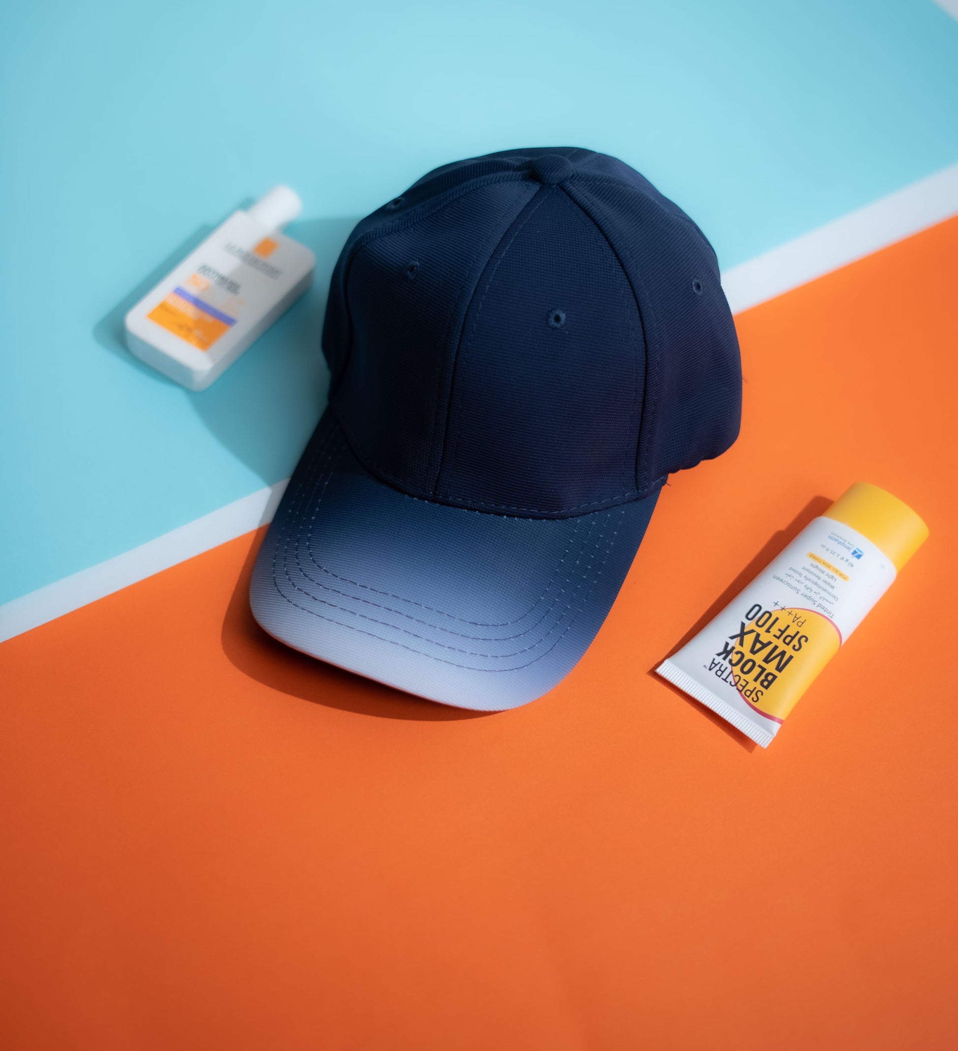 Navy blue cap on an orange and blue geometric-patterned surface with sunscreen bottles in Pakistan by Caps Nation