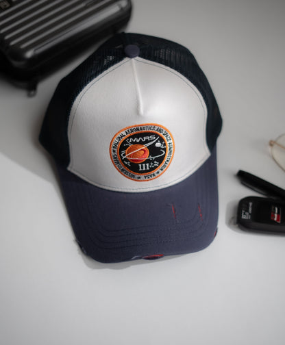 Navy and white cap with a logo on a light gray surface in Pakistan by Caps Nation