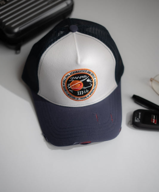 Navy and white cap with a logo on a light gray surface in Pakistan by Caps Nation