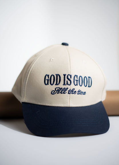 Beige and navy cap with 'GOD IS GOOD All the time' text on a white background in Pakistan by Caps Nation