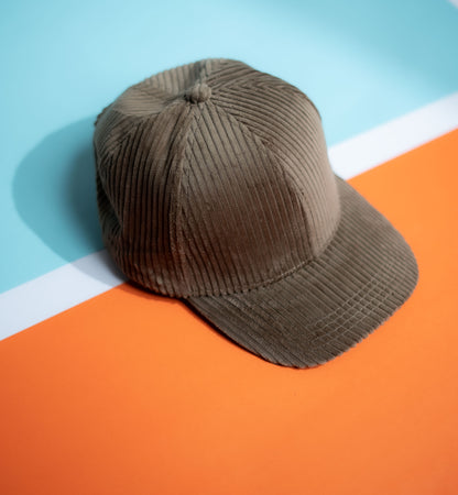 Brown corduroy cap on a colorful geometric background in Pakistan by Caps Nation