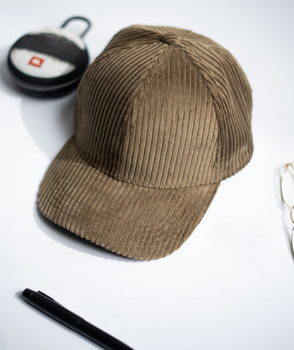 Beige corduroy cap on a white background with a pen and small round object in Pakistan by Caps Nation