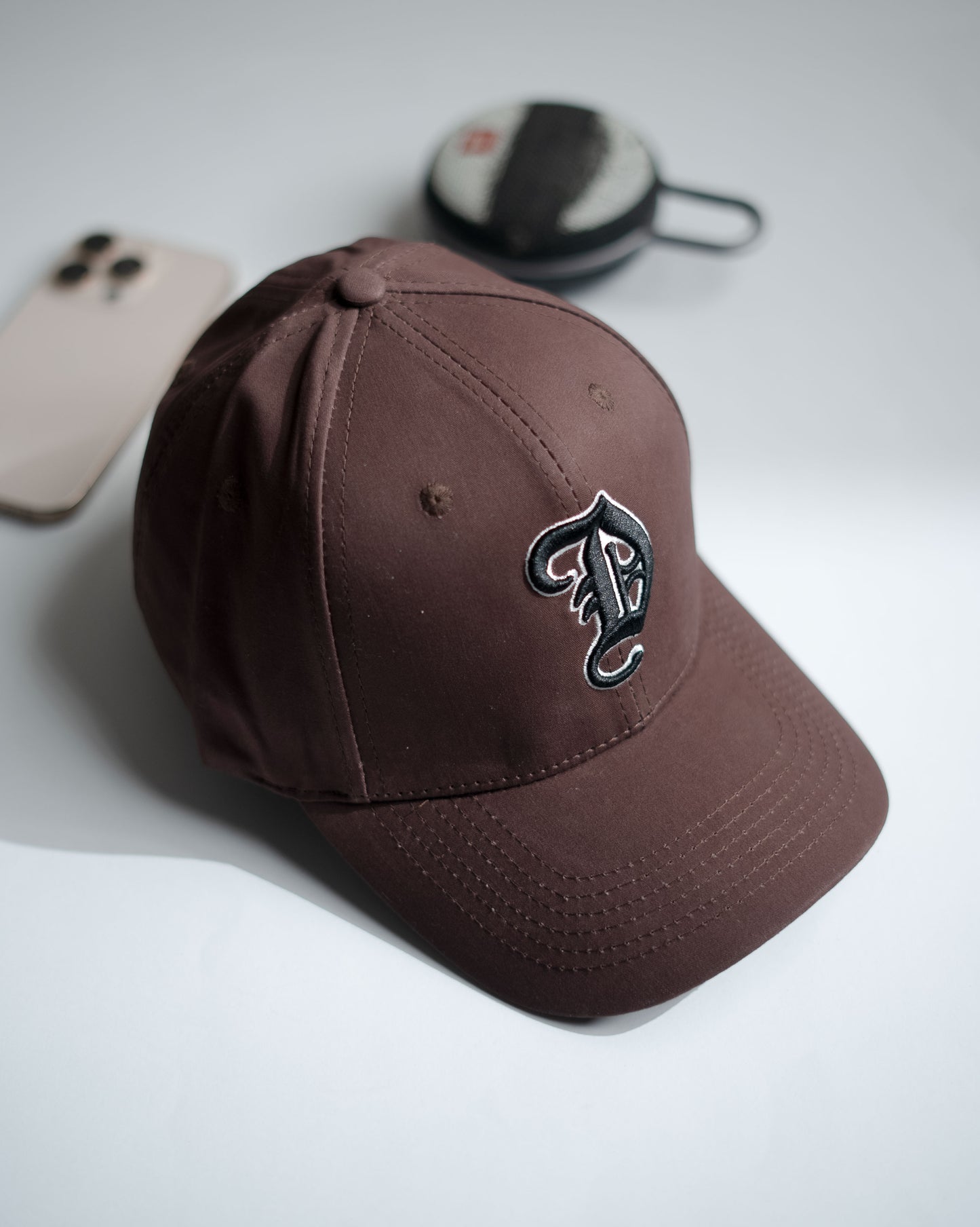 Brown cap with a logo on a light gray surface in Pakistan by Caps Nation