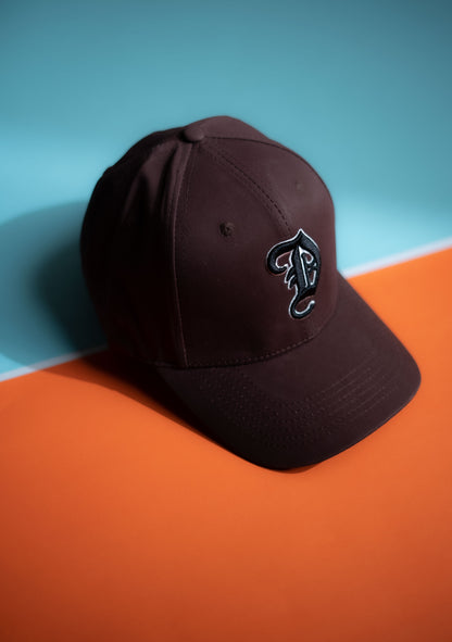 Brown cap with a logo on an orange and blue background in Pakistan by Caps Nation