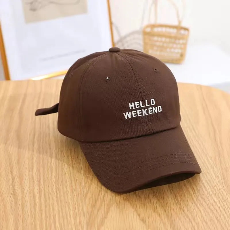 Brown cap with 'HELLO WEEKEND' text on a wooden surface in Pakistan by Caps Nation