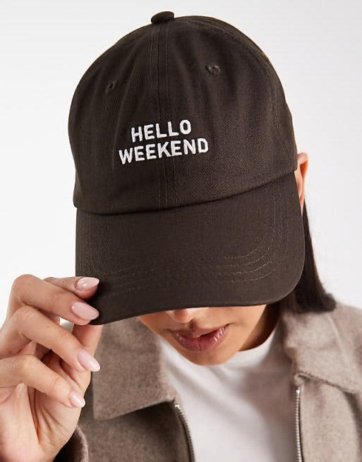 Person wearing a black cap with 'HELLO WEEKEND' text on a plain background in Pakistan by Caps Nation