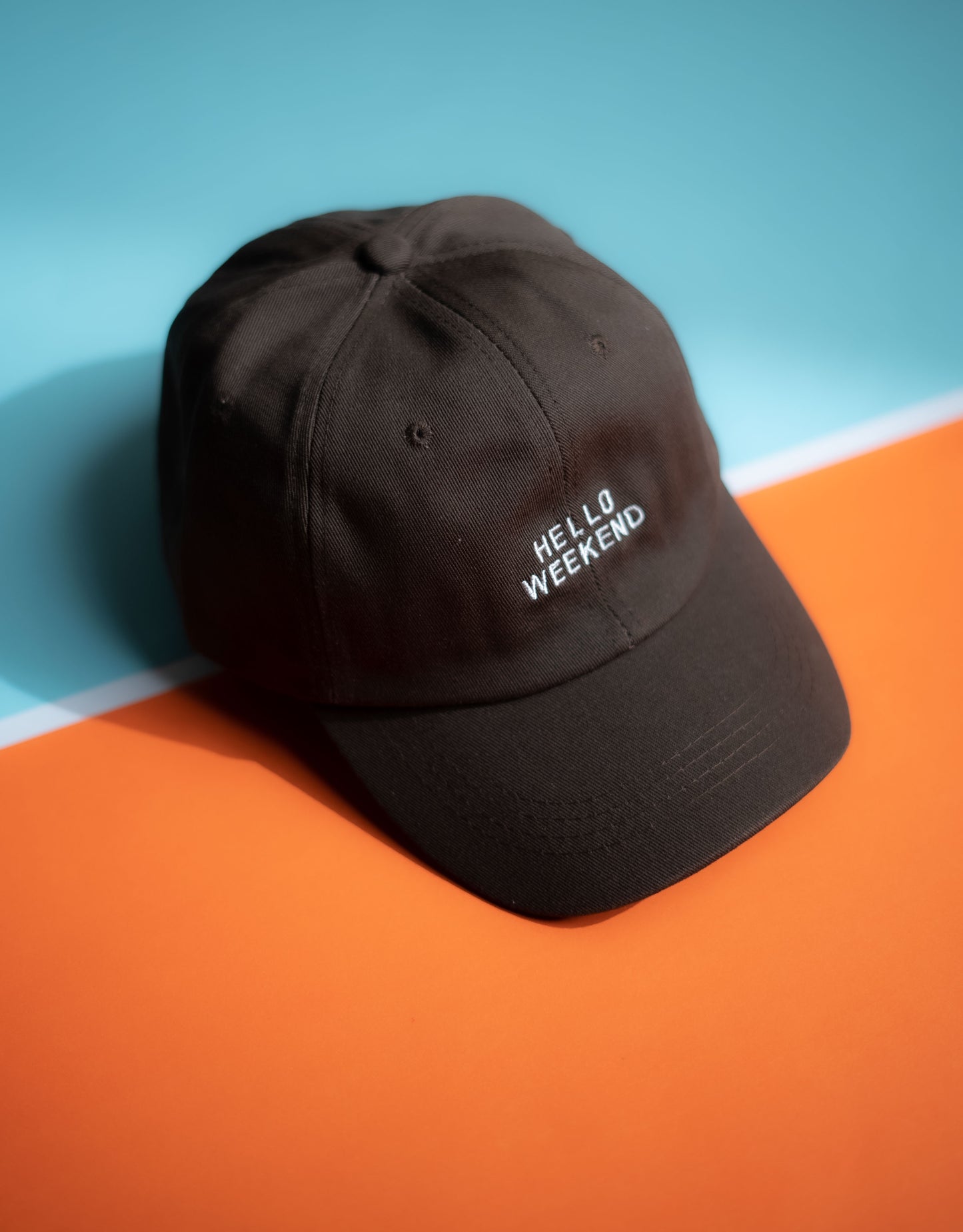 Black cap with 'Hello Weekend' text on a blue and orange background in Pakistan by Caps Nation