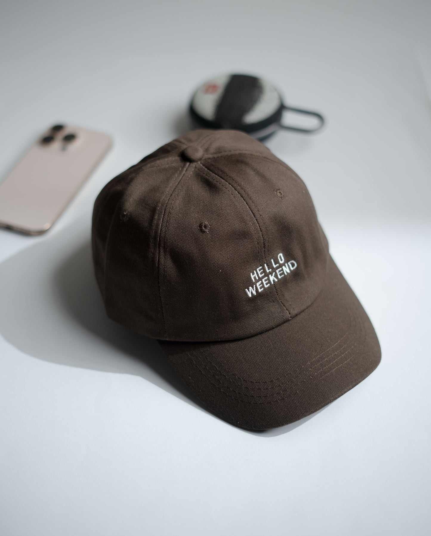 Brown cap with 'Hello Weekend' text on a light gray background in Pakistan by Caps Nation
