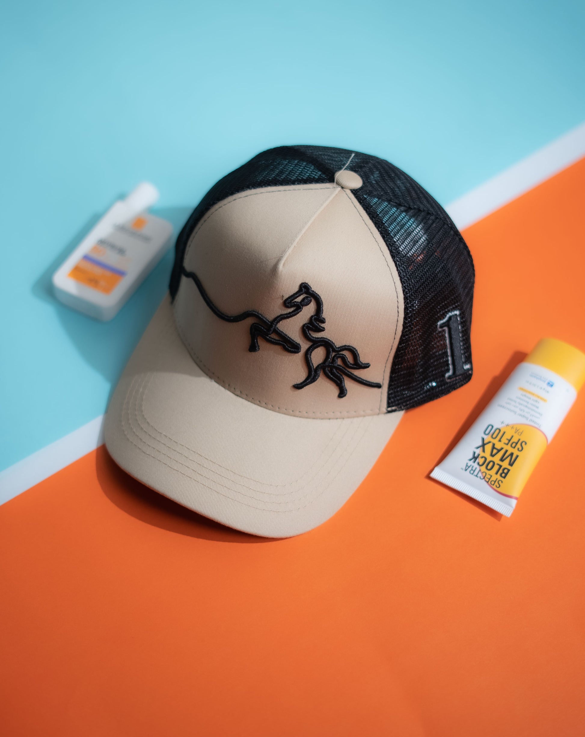 Beige and black cap with a logo on an orange and blue background in Pakistan by Caps Nation