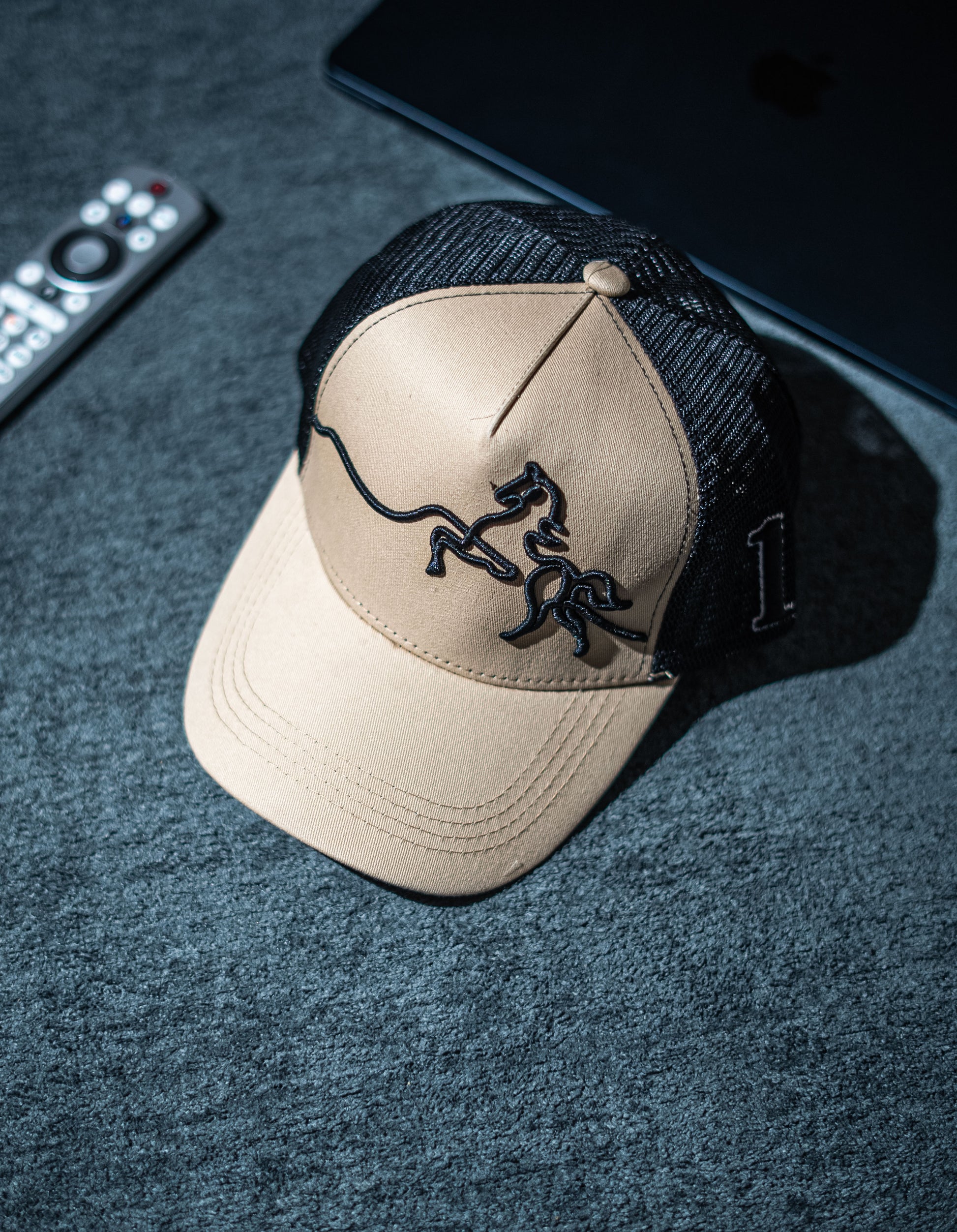 Beige cap with black logo on a dark textured surface in Pakistan by Caps Nation