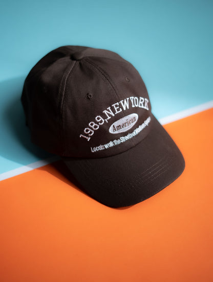 Black cap with '1989 New York' text on a blue and orange background in Pakistan by Caps Nation