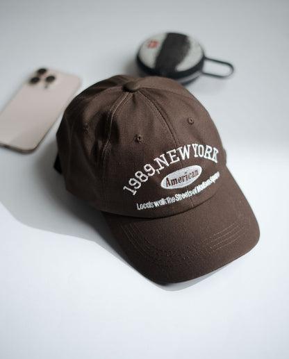 Brown cap with '1989 New York' text on a white surface in Pakistan by Caps Nation