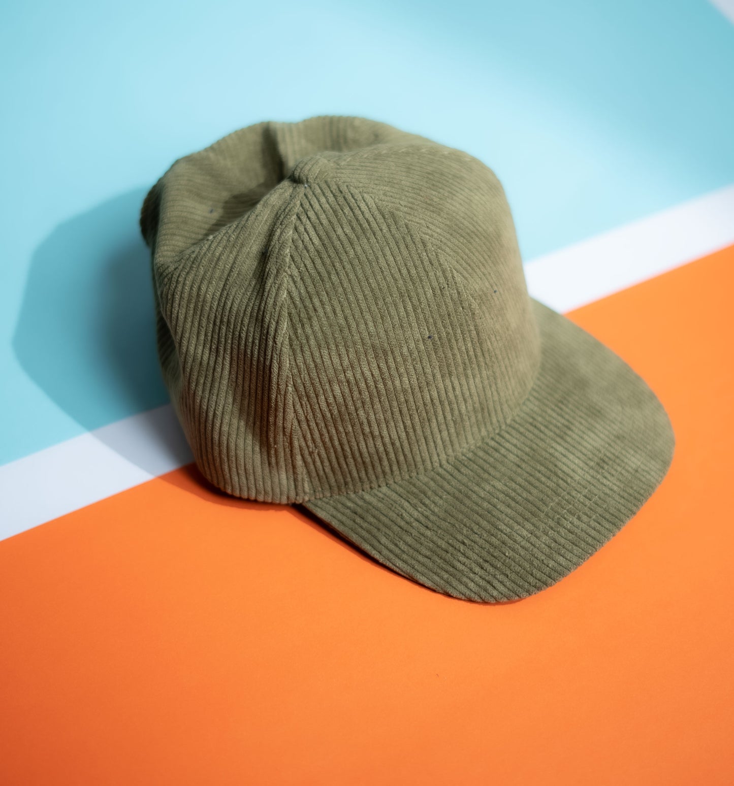 Green corduroy cap on a colorful geometric background in Pakistan by Caps Nation
