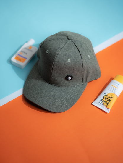 Green baseball cap on a blue and orange surface with a bottle and packet in the background in Pakistan by Caps Nation