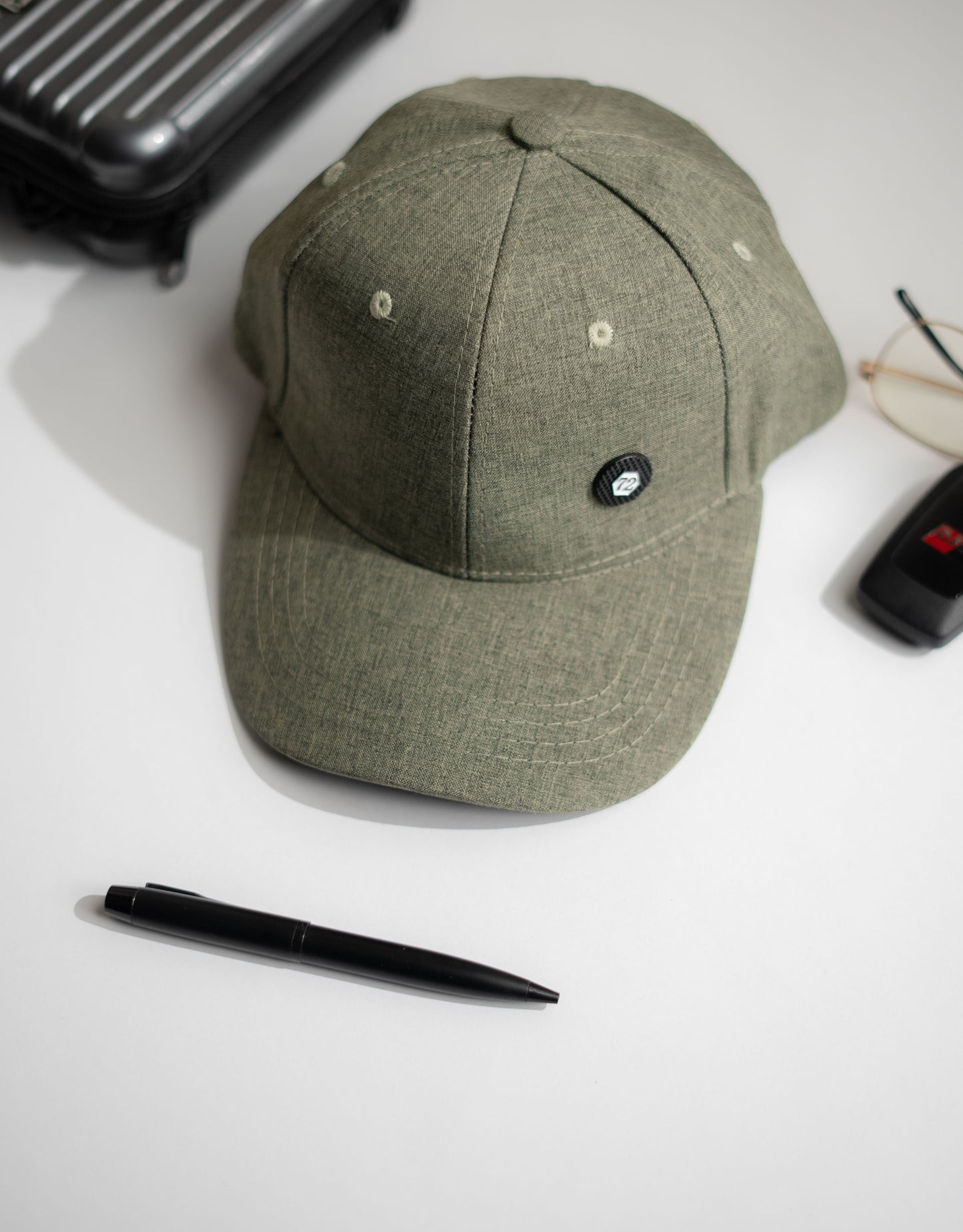 Green cap on a white surface with a pen and other items around in Pakistan by Caps Nation