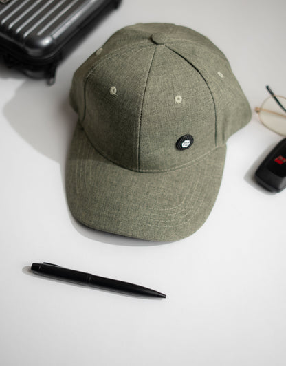 Green cap on a white surface with a pen and other items around in Pakistan by Caps Nation