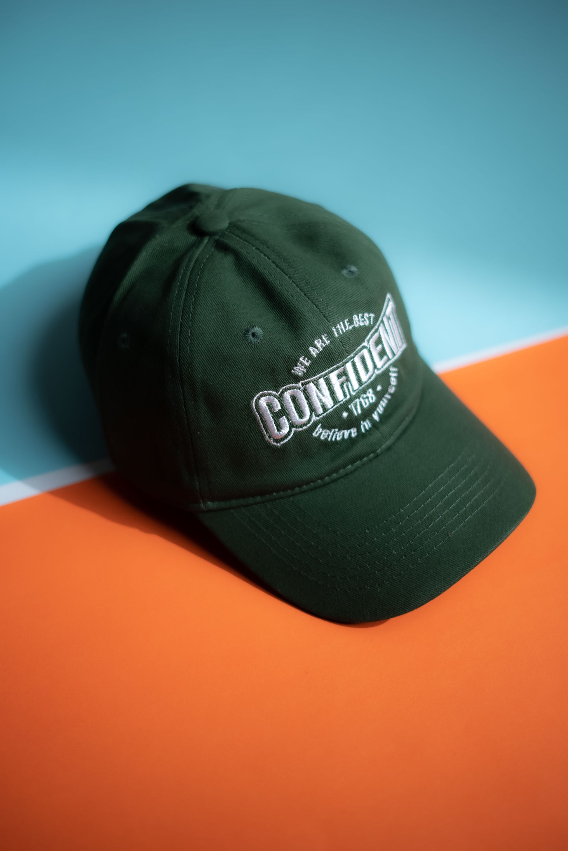 Green cap with white text on a blue and orange gradient background  in Pakistan by Caps Nation