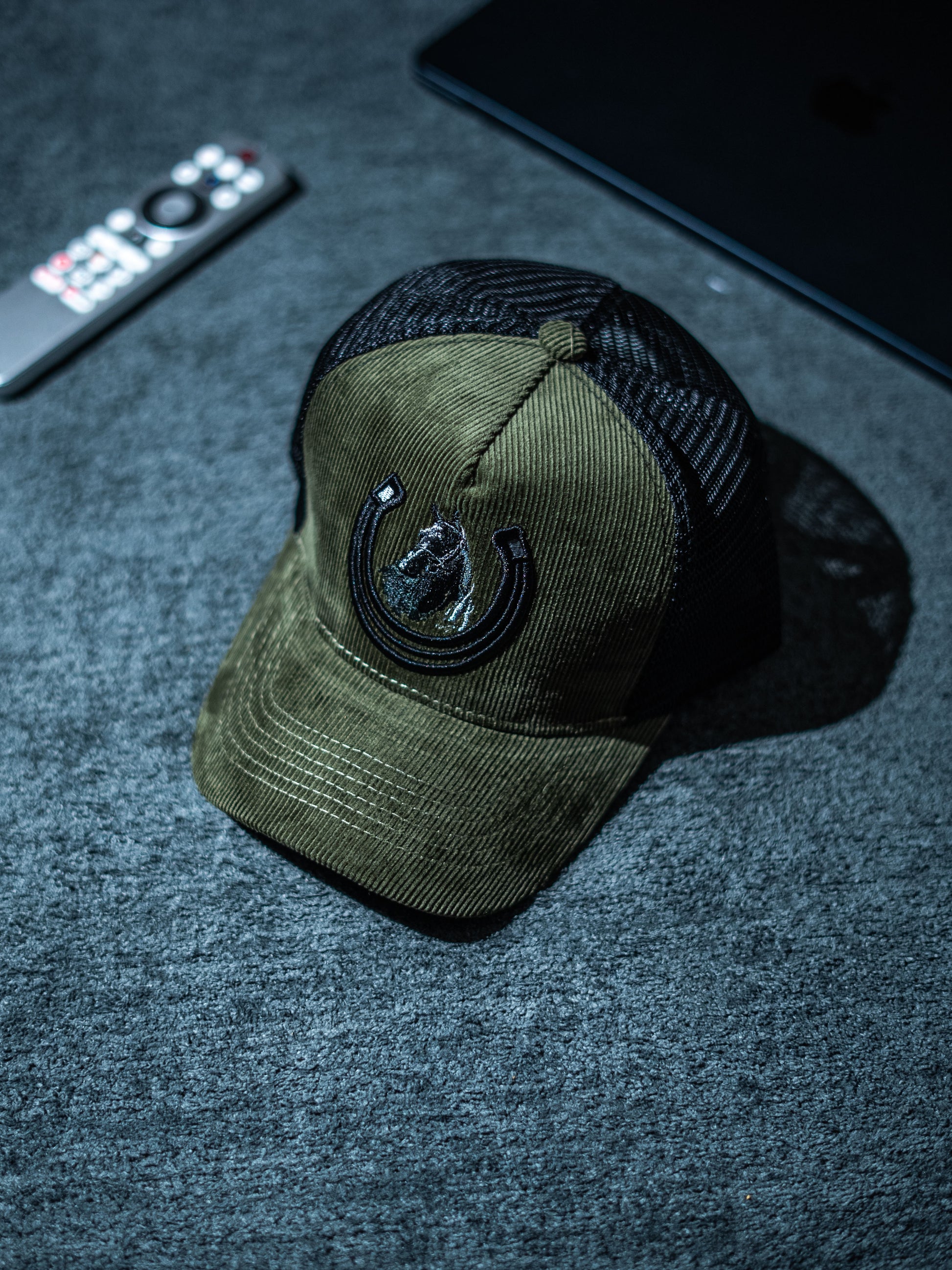Green cap with black mesh back on a dark textured surface in Pakistan by Caps Nation