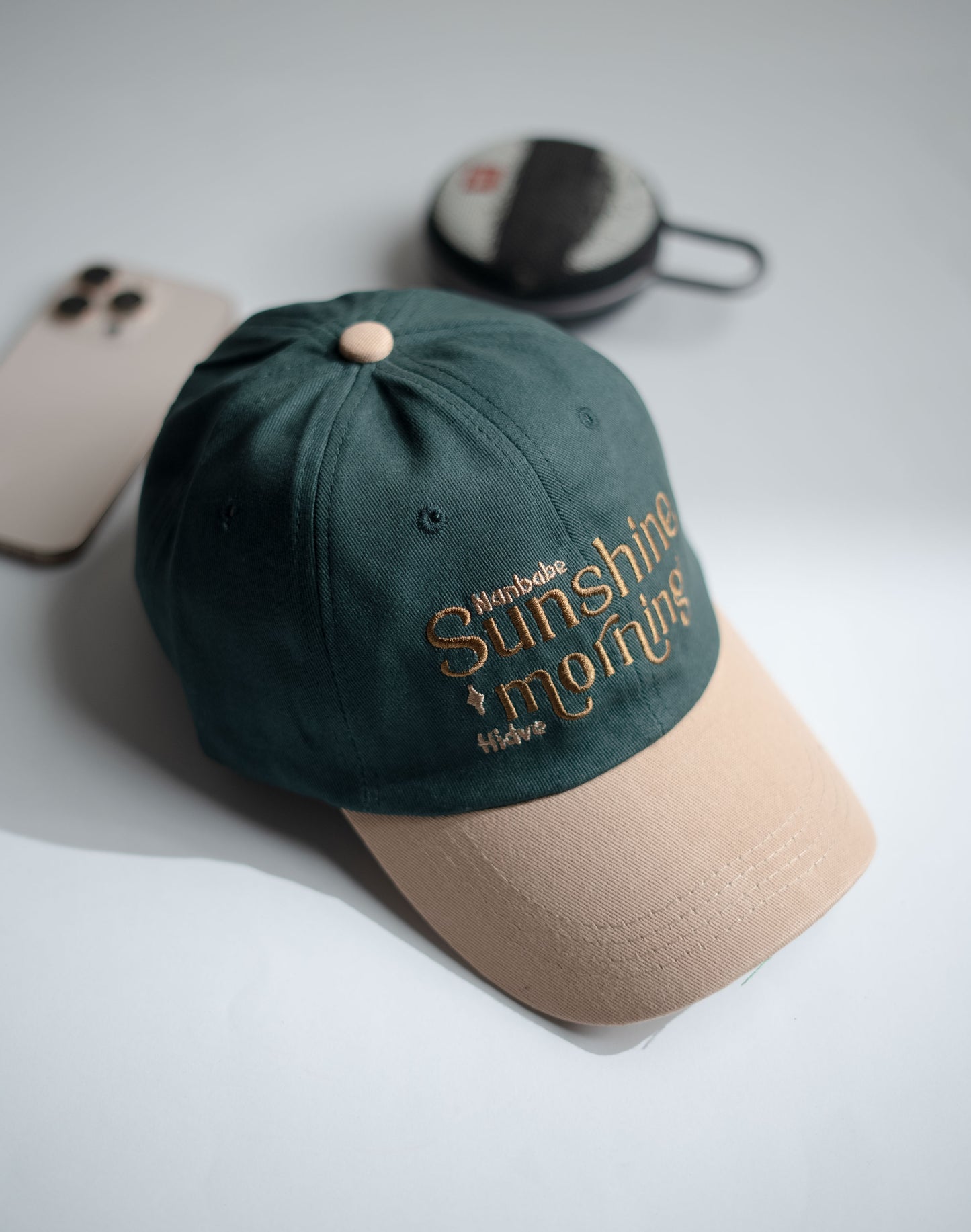 Green and beige cap with embroidered text on a light gray surface in Pakistan by Caps Nation
