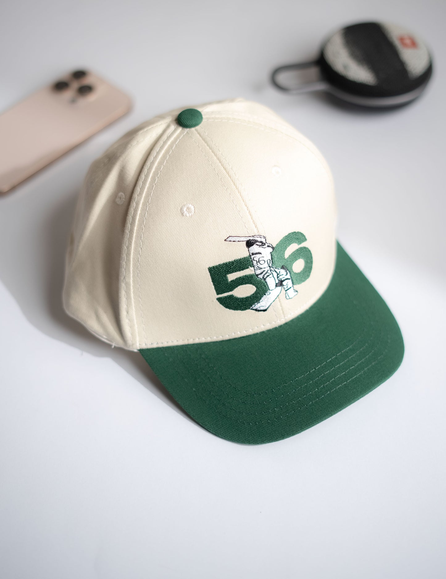 Beige and green baseball cap with number 56 and logo on a light gray background in Pakistan by Caps Nation