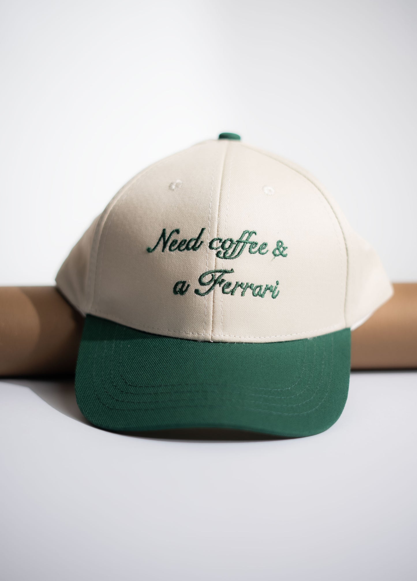 Beige and green cap with 'Need coffee & a Ferrari' text on a white background in Pakistan by Caps Nation