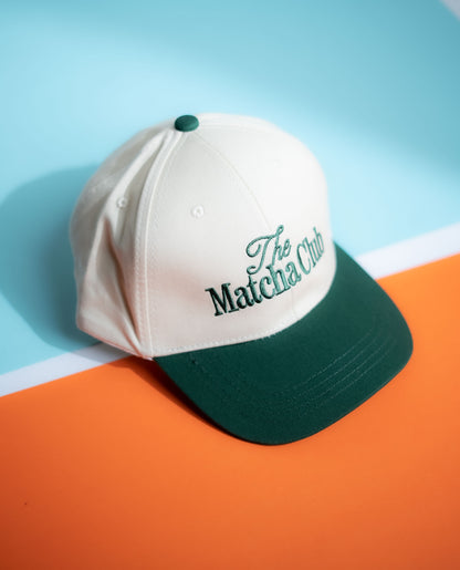 White and green cap with 'The Matcha Club' logo on a blue and orange background in Pakistan by Caps Nation