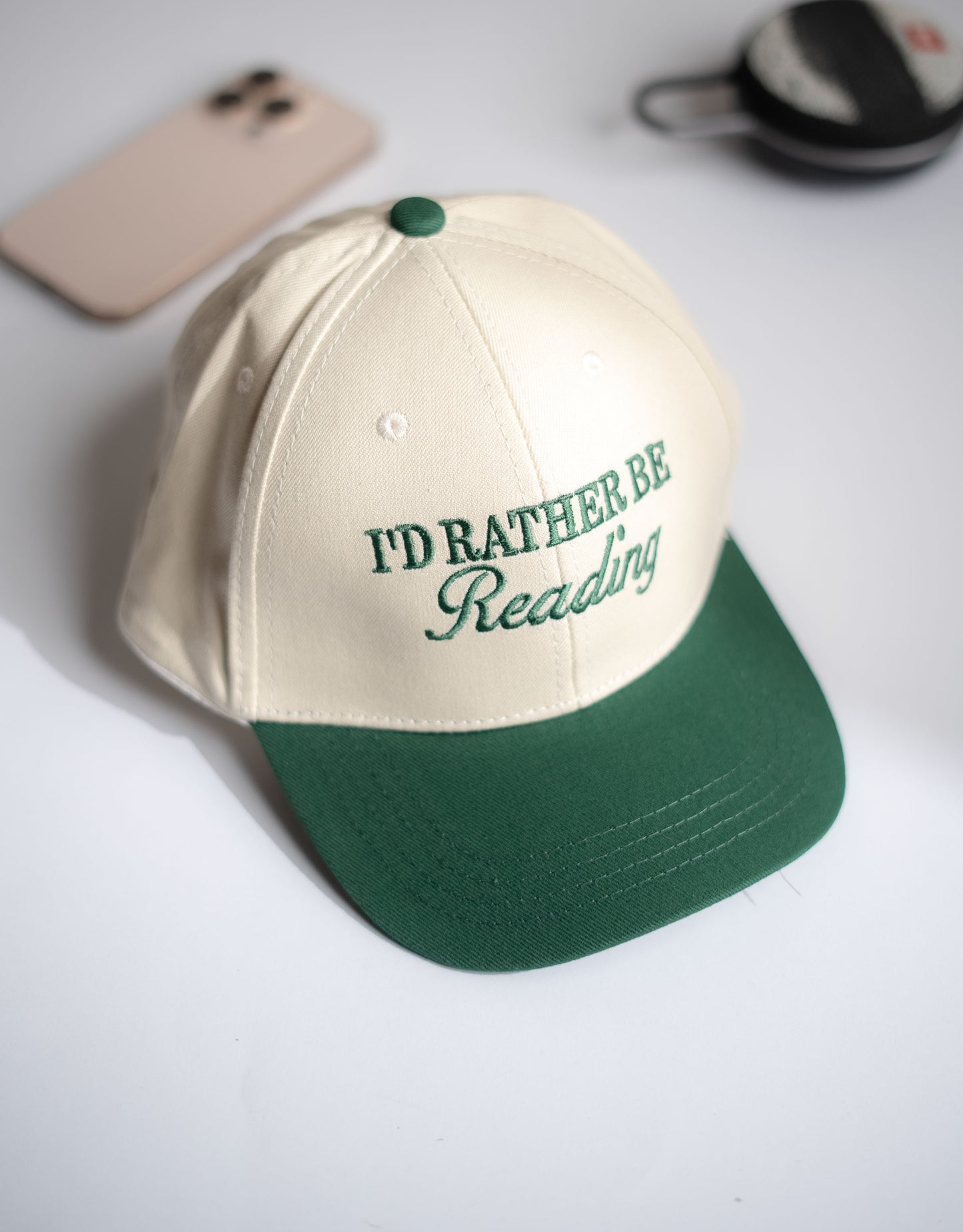 Cap with 'I'd Rather Be Reading' text on a white surface in Pakistan by Caps Nation