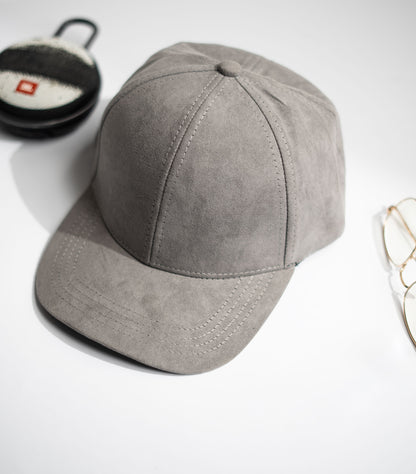 Gray baseball cap on a white background with a cup and glasses partially visible in Pakistan by Caps Nation