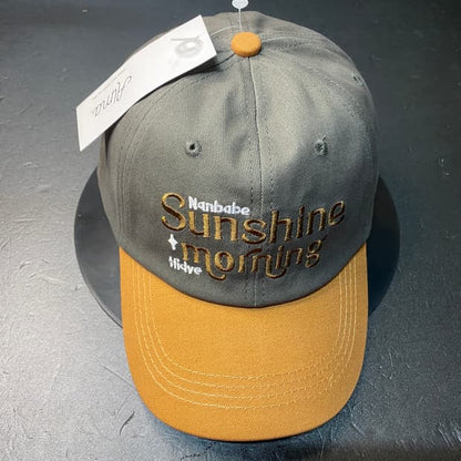 Gray and yellow cap with embroidered text on a dark surface in Pakistan by Caps Nation