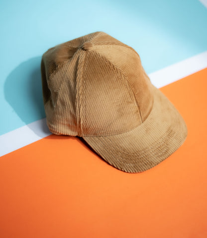 Brown corduroy cap on a colorful geometric background in Pakistan by Caps Nation