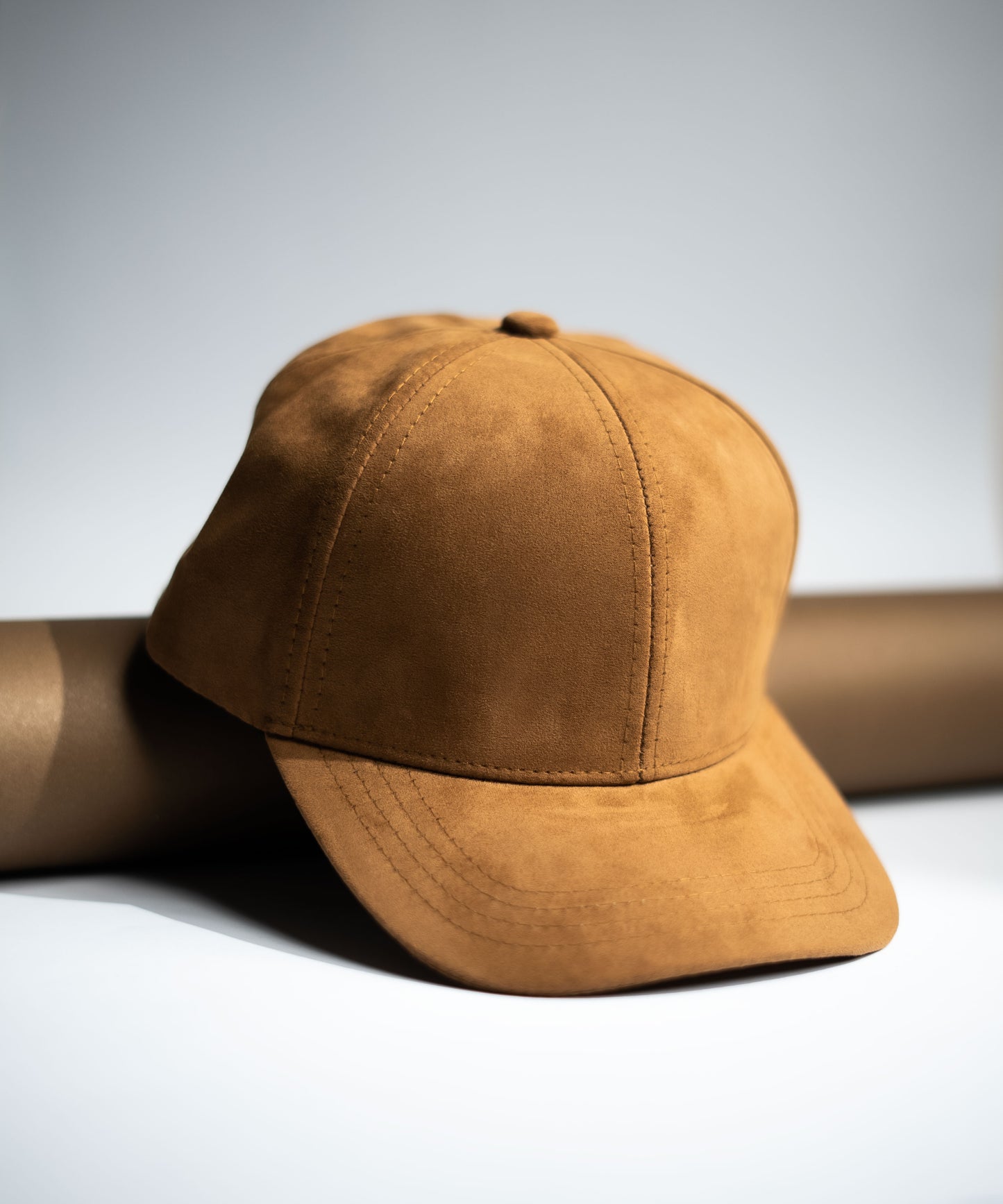 Brown suede cap on a light gray background in Pakistan by Caps Nation
